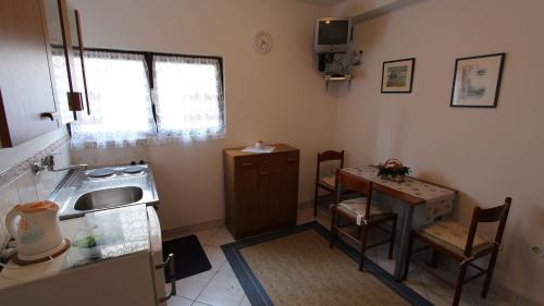a small kitchen with a sink and a table at Apartments Trupec in Malinska