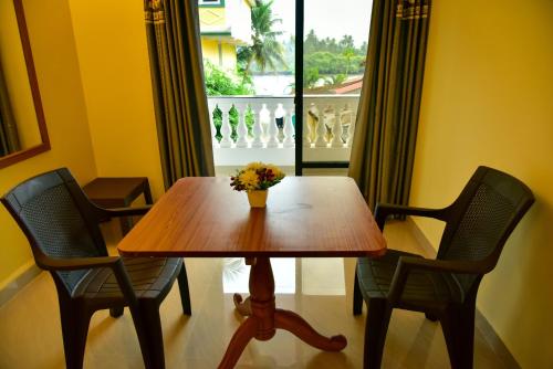 a table with two chairs and a vase of flowers on it at Valeria's Holiday Home in Cavelossim