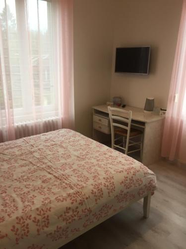 a bedroom with a bed and a desk and a television at La Vie est Belle in Abbeville