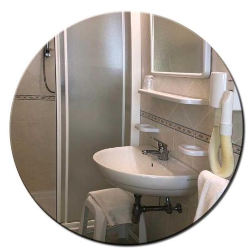a mirror reflecting a bathroom with a sink and a shower at Hotel Amedea in Cervia