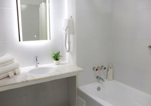 a white bathroom with a sink and a phone at Suites Inkari in Lima