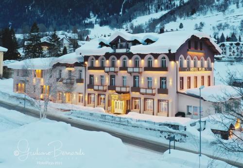 a large building in the snow with lights at Hotel Pejo in Peio Fonti