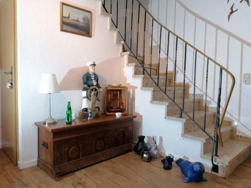 un homme assis sur une commode sous un escalier dans l'établissement Hotel Pension garni Haus am Strand, à Norddeich