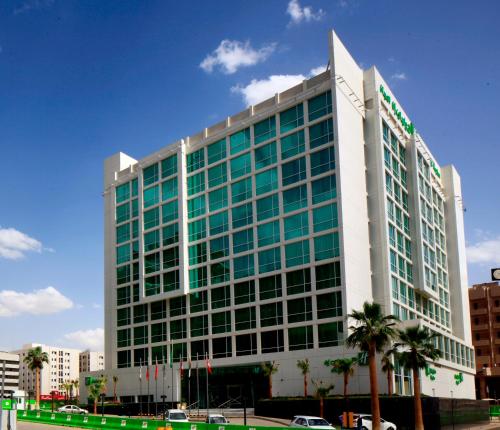 un grande edificio con finestre verdi su una strada cittadina di Holiday Inn Meydan, an IHG Hotel a Riyad