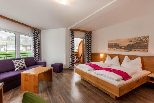 a bedroom with a large bed and a couch at Hotel Winterer in Schladming