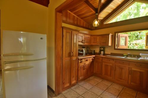 a kitchen with a white refrigerator and wooden cabinets at Mirador House, Cozy Private Home W- Volcano View in El Castillo de la Fortuna