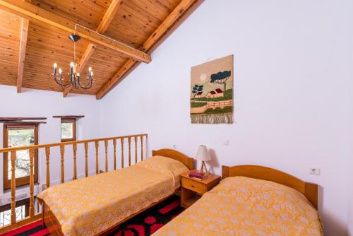 a bedroom with two beds and a wooden ceiling at La Maison de Penelope in Límnai