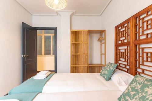 a bedroom with a white bed with a wooden headboard at Apartamento KUIA con vistas frontales a la Ría de Bilbao cerca del metro in Erandio