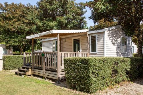 a small house with a porch in a yard at Camping de Châlons-en-Champagne in Châlons-en-Champagne