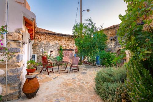 a patio with chairs and a table in a stone building at La Maison de Penelope in Límnai