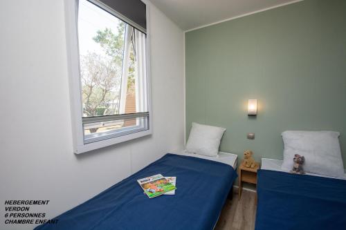 une chambre avec deux lits et une fenêtre dans l'établissement Camping International d'Aups, à Aups