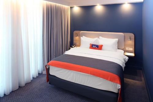 a hotel room with a bed with a red pillow on it at Holiday Inn Express - Ljubljana by IHG in Ljubljana