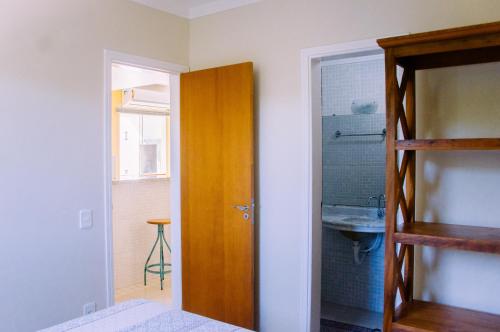 uma casa de banho com uma porta de madeira e um lavatório em Apto no Itaguá, 2 dts, wifi, piscina e ar condicionado em Ubatuba
