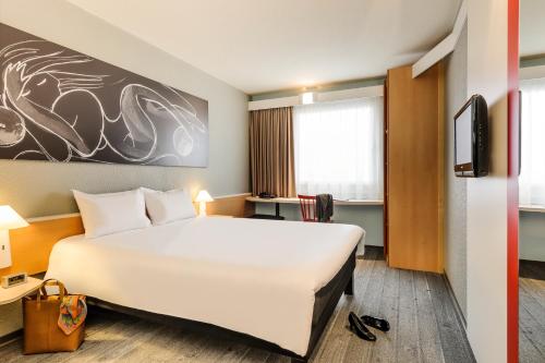 a hotel room with a large white bed and a desk at ibis Hotel Hannover City in Hannover