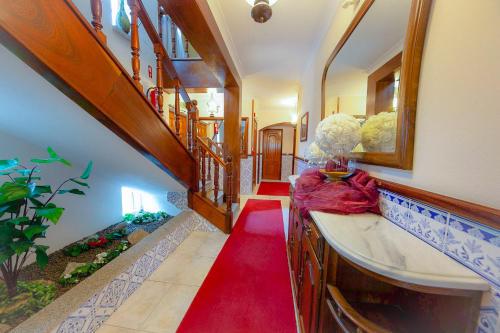 d'un couloir avec moquette rouge et d'une salle de bains avec lavabo. dans l'établissement Beira Dão - Turismo Rural, à Tondela