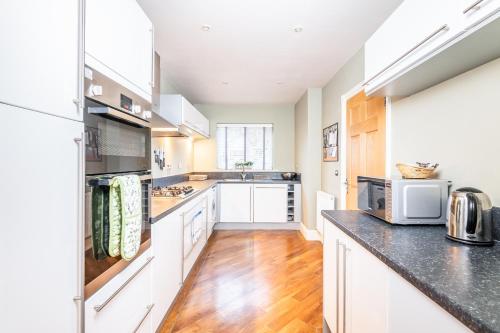 a kitchen with white cabinets and a black counter top at 9 College Court Spacious, Modern 4-Bed Townhouse in York - Pass the Keys in York