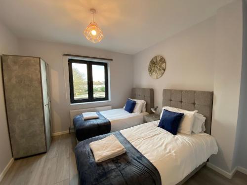 1 dormitorio con 2 camas y ventana en Zen Quality flats near Heathrow that are Cozy CIean Secure total of 8 flats group bookings available, en Hounslow