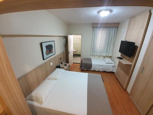 um pequeno quarto com 2 camas e uma televisão em Via Contorno Hotel em Belo Horizonte