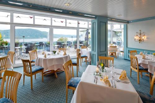 a restaurant with white tables and chairs and windows at PlusNaturHotel direkt am Ederseeufer Waldhotel Wiesemann und Ferienapartments in Waldeck