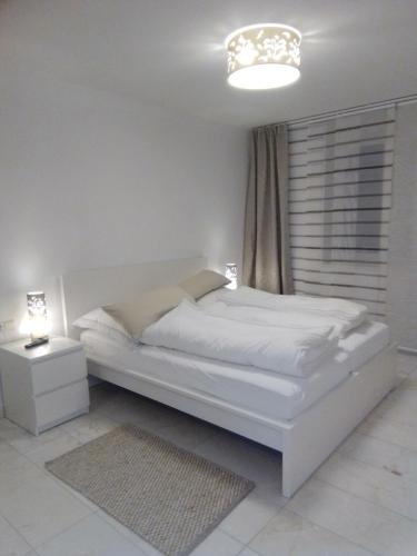 a white bedroom with a white bed and a chandelier at Villa Bellevue in Waldkappel