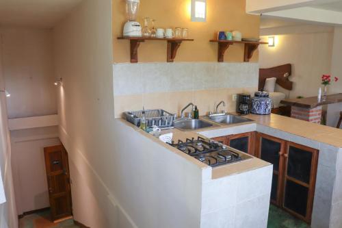 a kitchen with a sink and a stove at Hostal & Suites Pata de Perro in Bacalar