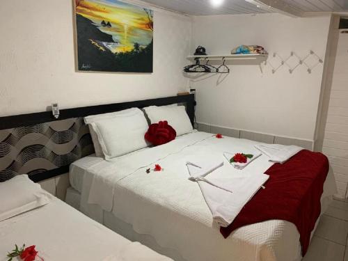 a bedroom with two beds with red roses on them at Residência da Cláudia in Fernando de Noronha