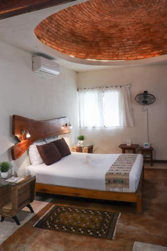 a bedroom with a large bed and a large ceiling at Hostal & Suites Pata de Perro in Bacalar