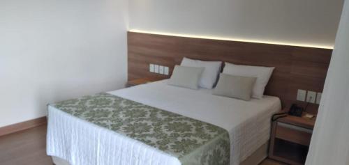 a bedroom with a white bed with a wooden headboard at Cond VISTA AZUL in Pedra Azul