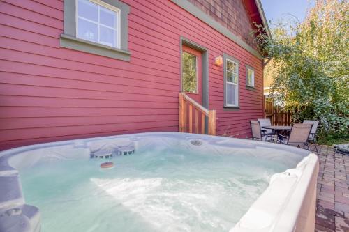 a hot tub in front of a red house at Georgia Peach - Meredith Lodging in Bend