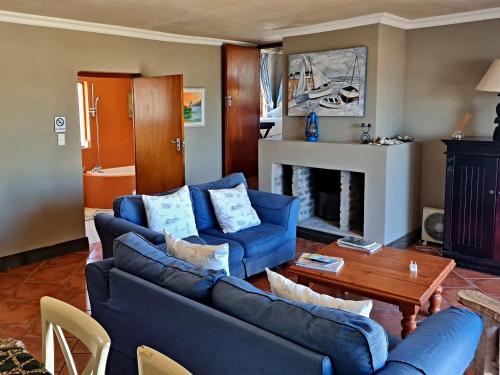 sala de estar con 2 sofás azules y chimenea en Walkerbay Accommodation en Gansbaai