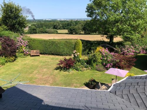 a patio with an umbrella and a lawn with flowers at Trumbles Gatwick B&B in Charlwood