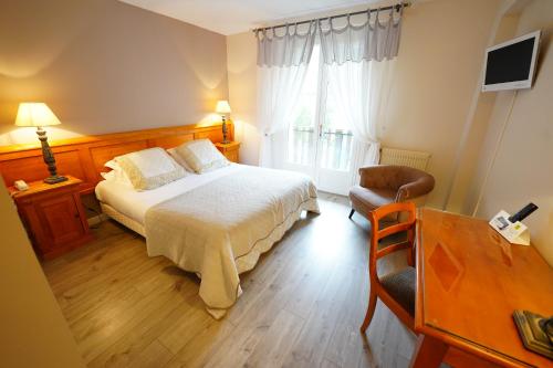 een slaapkamer met een bed, een stoel en een raam bij Logis Hôtel Le Griou in Saint-Jacques-des-Blats