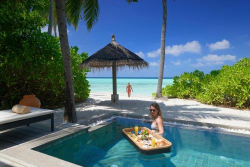 a woman sitting in a swimming pool at a resort at NH Collection Maldives Havodda Resort - Stays of 6 nights or more, 50 percent off domestic flights for 2 person in Gaafu Dhaalu Atoll