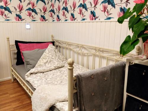 - un lit dans un dortoir avec un mur fleuri dans l'établissement Wanha kunnantalo, à Pudasjärvi