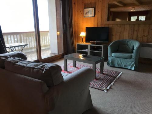 a living room with a couch and a tv and a table at Chalet du grand cerf in Servoz
