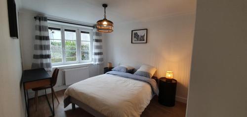 a bedroom with a bed and a desk and a window at Sur La Route Des Myrtilles in Gouézec