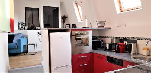une cuisine avec des armoires rouges et un réfrigérateur blanc dans l'établissement ATIPIKE Appart Béthune centre, à Béthune