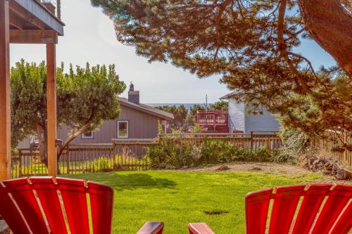 two red chairs in a yard with a house at Sandy Feet in Nehalem