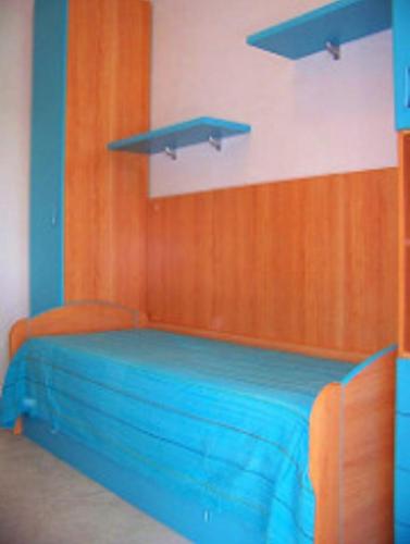a bedroom with a blue bed and a wooden wall at Villa Rinaldi apartment in Vieste