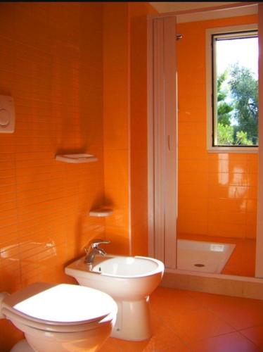 an orange bathroom with a toilet and a sink at Villa Rinaldi apartment in Vieste