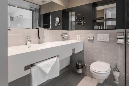 a bathroom with a toilet and a sink and mirror at Pearl Design Hotel - Frankfurt City in Frankfurt/Main