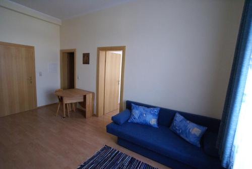 a living room with a blue couch and a table at Appartement zur Post in Ferlach