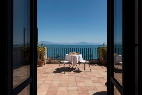 a table on a balcony with a view of the ocean at Palazzo Suriano Heritage Hotel in Vietri sul Mare