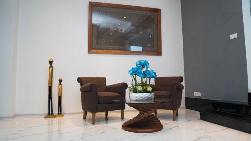 a living room with two chairs and a table with blue flowers at Liberdada Villa SURINAME in Wanica