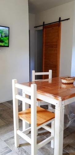a wooden table with two white chairs and a table and a table and chairsktop at La Soñada - cabañas in Cruz del Eje