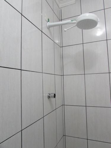 ducha de azulejos blancos con cabezal de ducha en Hotel Ideal Flíper com Estacionamento Grátis para carro pequeno altura padrão "INTERNET FIBRA", en São Paulo