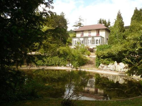 une maison avec un étang en face d'une maison dans l'établissement La Pluie de Roses, à Giverny