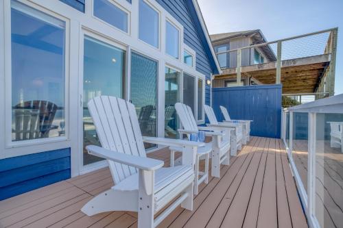 a row of white chairs sitting on a deck at Beauty On The Beach in Depoe Bay