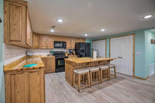 a large kitchen with wooden cabinets and bar stools at Outdoor Family Fun Large Home by Beaver Lake! in Eureka Springs