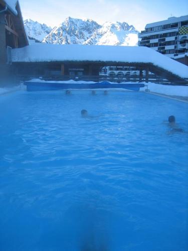 un groupe de personnes se baignant dans une piscine dans la neige dans l'établissement Skis aux pieds station 1600 Sun Vallée, à Puy-Saint-Vincent